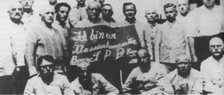 "Ich bin ein klassenbewußter SPD-Bonze". Nazi-Propagandabild mit bayerischen SPD-Funktionären 1933 im KZ Dachau, dritter von links der Pasinger SPD-Landtagsabgeordnete Hans Nimmerfall.